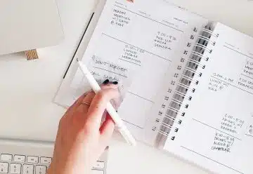 person holding notepad and pen flat lay photography