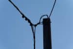a telephone pole with wires and a blue sky in the background
