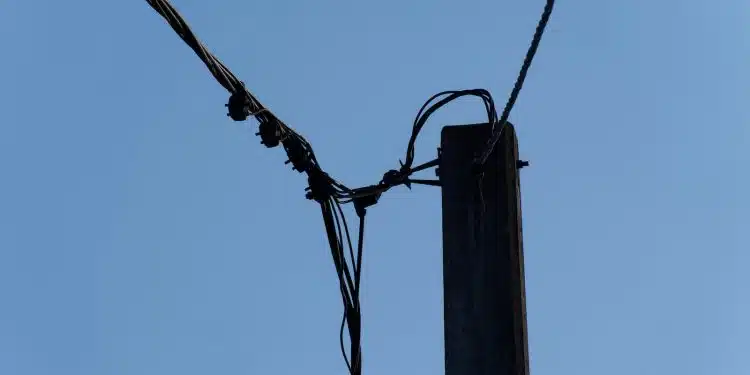 a telephone pole with wires and a blue sky in the background